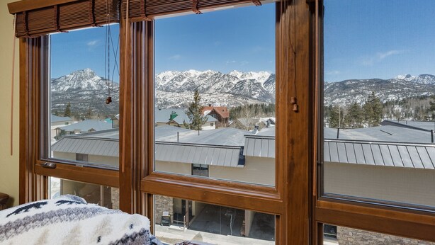 A room with a large window offering a view of snow-covered mountains and a residential area. - Purgatory townhome with Easy Access to Slopes - Views - EV Charger (Durango)