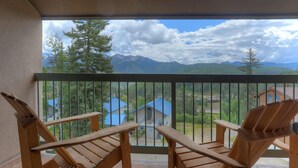 A balcony with two wooden rocking chairs, a view of mountains, and a blue-roofed building in the background. - Double Diamond | Walk to Ski Lift & Pool Access - Mtn Views, Fireplace (Durango)