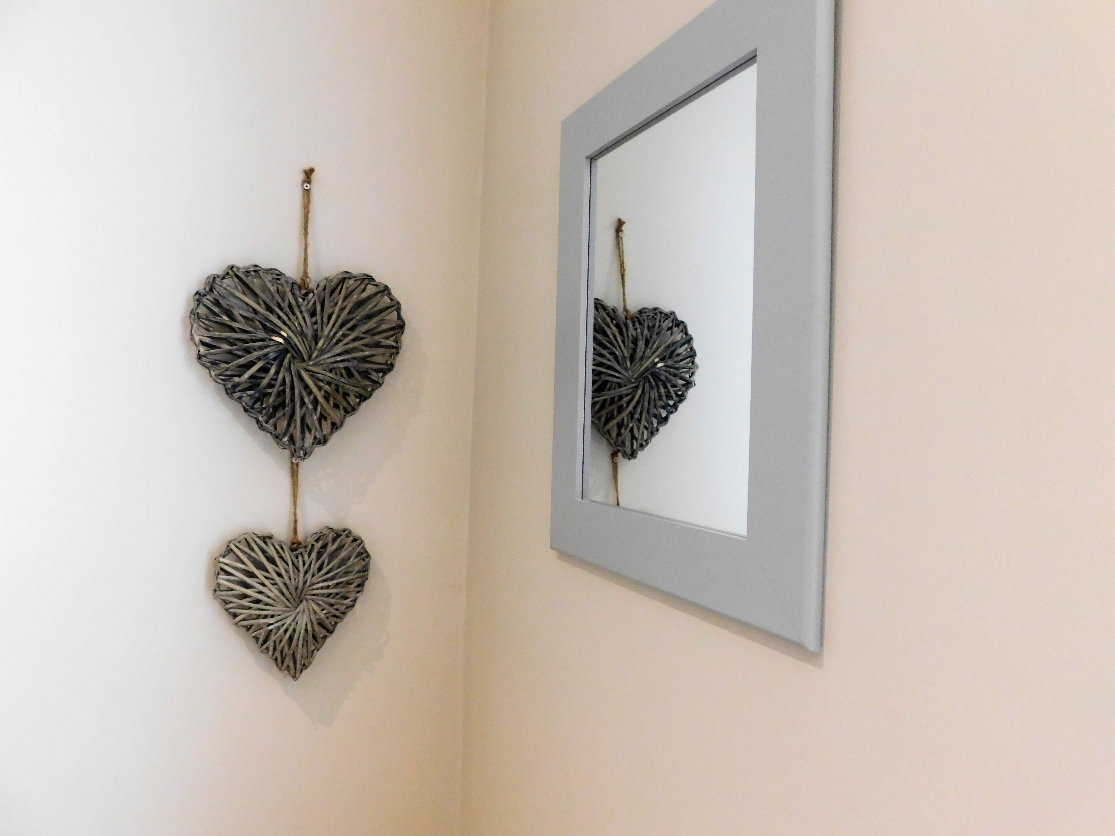 A wall with two heart-shaped wall art pieces and a mirror.