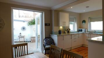 A compact kitchen with a dining area, a window with blinds, and a view of the outside.