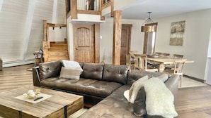 A modern living room with a sectional sofa, a wooden coffee table, and a dining area with a wooden table and chairs. - 6 bedroom modern West Vail Home w/2 large decks, 300 yds from Vail free shuttle (Vail)