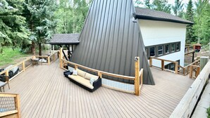 A modern building with a sloped roof, a deck with wooden railings, and a seating area with a sofa and chairs. - 6 bedroom modern West Vail Home w/2 large decks, 300 yds from Vail free shuttle (Vail)