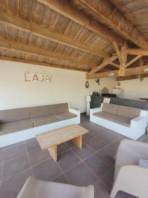 A rustic interior with wooden beams, a sofa, a bench, and a kitchenette area. - Caja Villa – Family home for 10 people with a heated pool in Brétignolles (Bretignolles-sur-Mer)