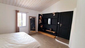Une chambre à coucher avec un lit, une armoire, un miroir et une fenêtre avec des rideaux.