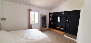 Une chambre à coucher avec un lit, une armoire, un miroir et une fenêtre avec des rideaux.