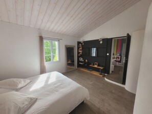 Une chambre à coucher avec un lit, une grande fenêtre, un téléviseur et un miroir.