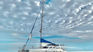A sailboat named 'LOST OCT' on calm waters with a partly cloudy sky. - Stay & Sail! Overnight Live-Aboard Experience in Bonaire (Kralendijk)