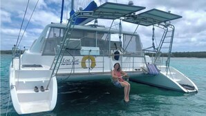 A person sitting on a catamaran with a lifebuoy and a logo on the side. - Stay & Sail! Overnight Live-Aboard Experience in Bonaire (Kralendijk)
