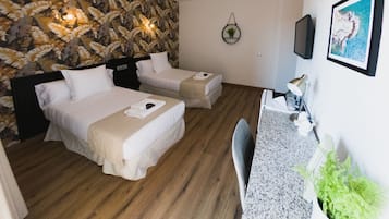 A hotel room with two beds, a small desk, a wall-mounted TV, and a framed picture.