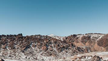 A rugged mountainous landscape with rocky terrain and sparse snow coverage.