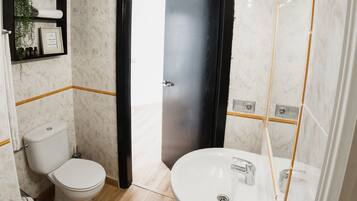 Un baño moderno con inodoro, lavabo y zona de ducha.