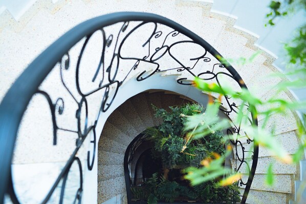 A stone archway with a metal railing and greenery inside.