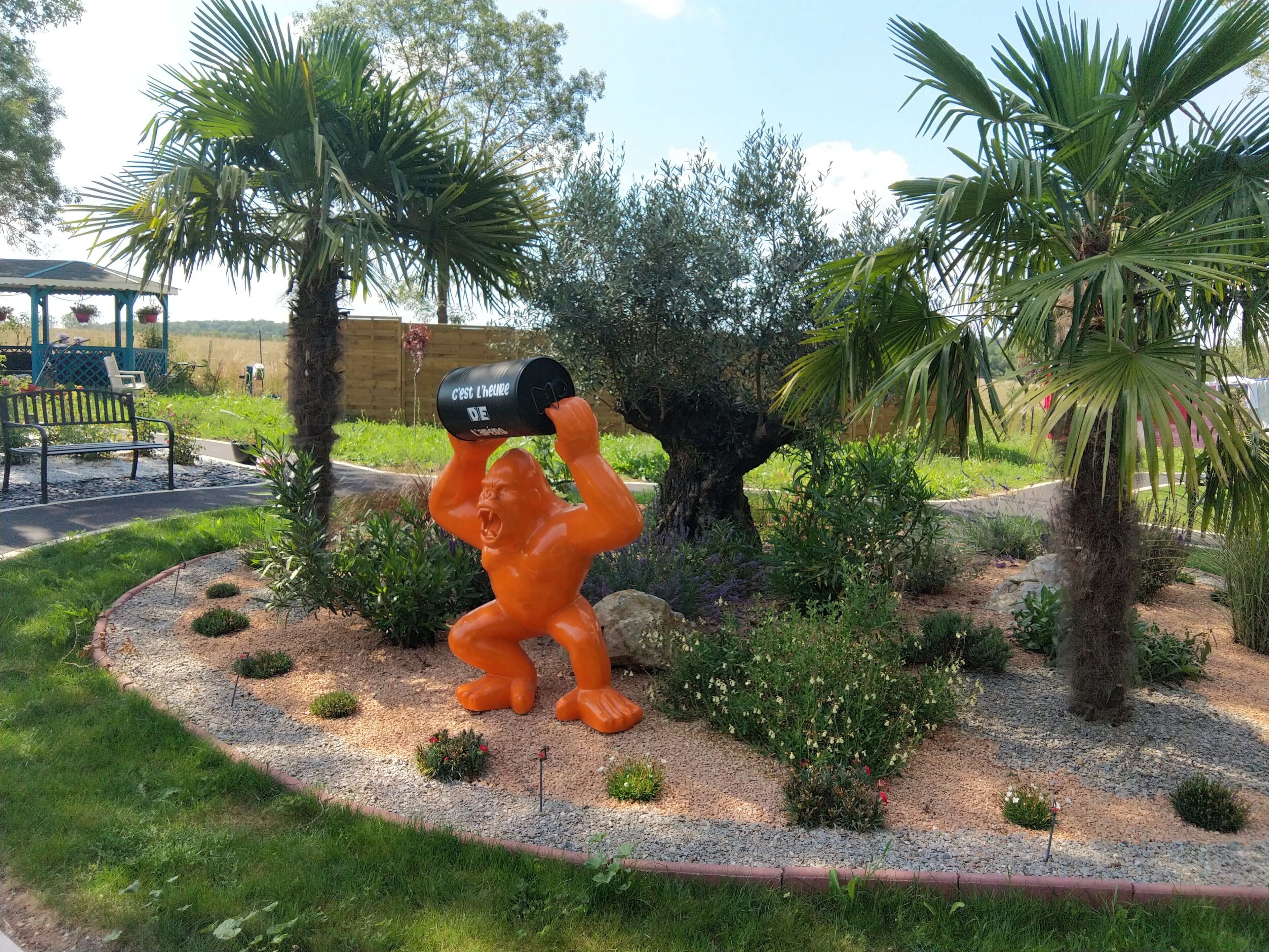 A garden with a central sculpture of a gorilla holding a can.