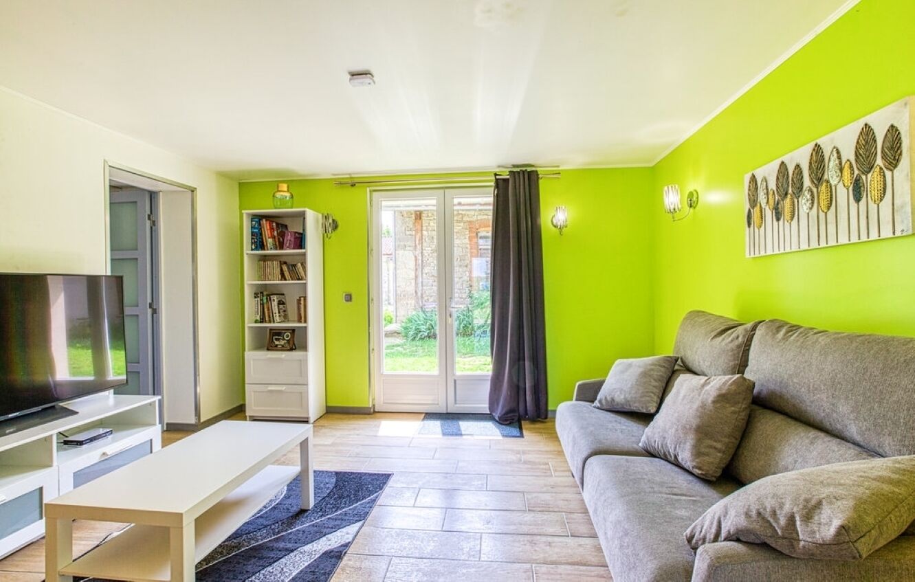 A living room with a sofa, TV, bookshelf, and a door leading to a balcony.