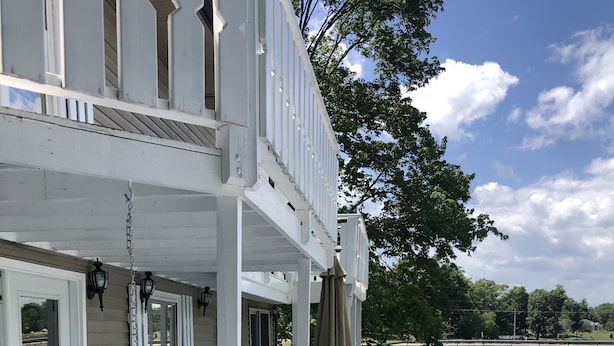 Eine überdachte Außenterrasse mit Seeblick, mit einer Sitzecke inklusive Stühle und Tisch, sowie eine weitere überdachte Terrasse mit Tisch und Stühlen.