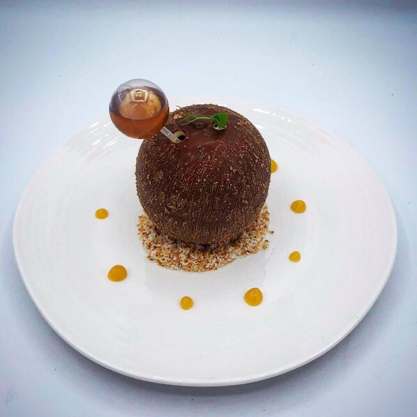 A dessert on a white plate with a clear glass and a sprig of mint.