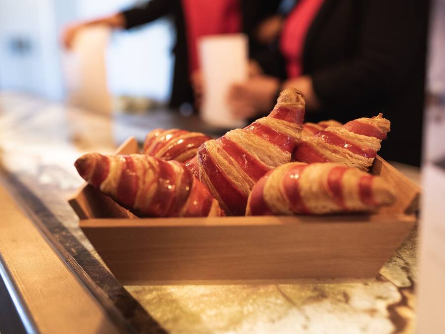 Uma bandeja de madeira com croissants envoltos em bacon.