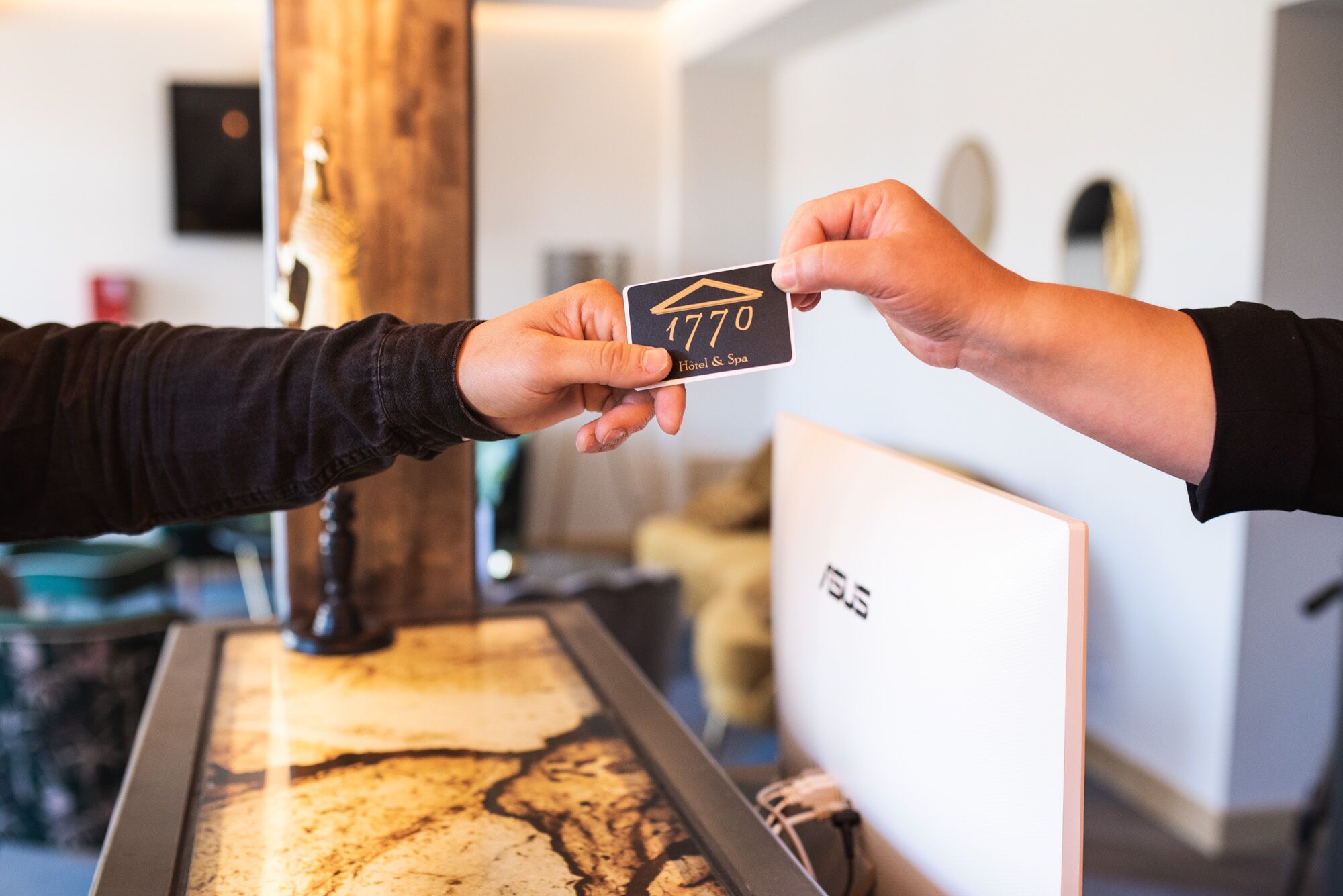 A person handing over a black card with '1770' and 'Hotel & Spa' to another person.