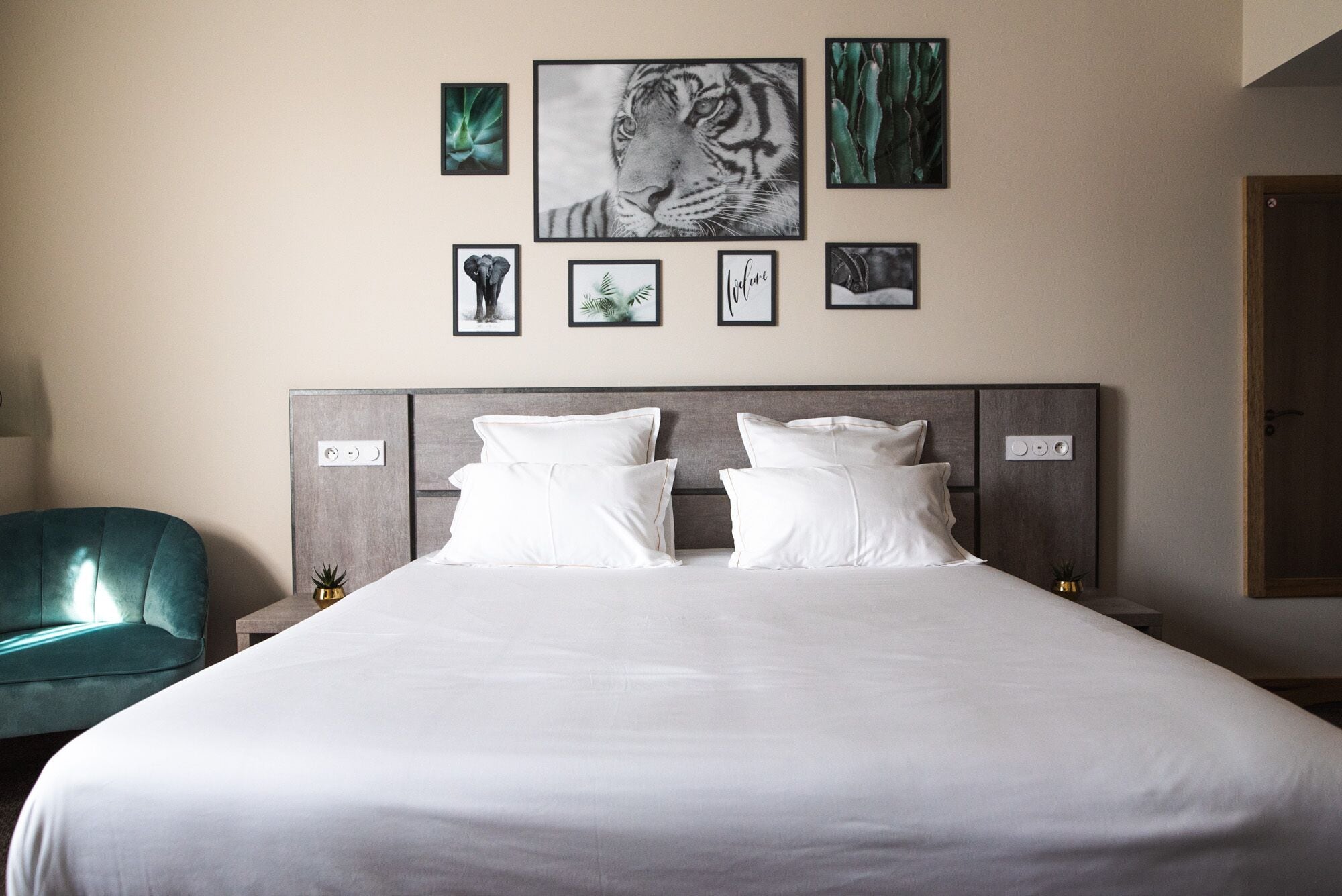 A bedroom with a large bed, two white pillows, a grey headboard, and a teal armchair.