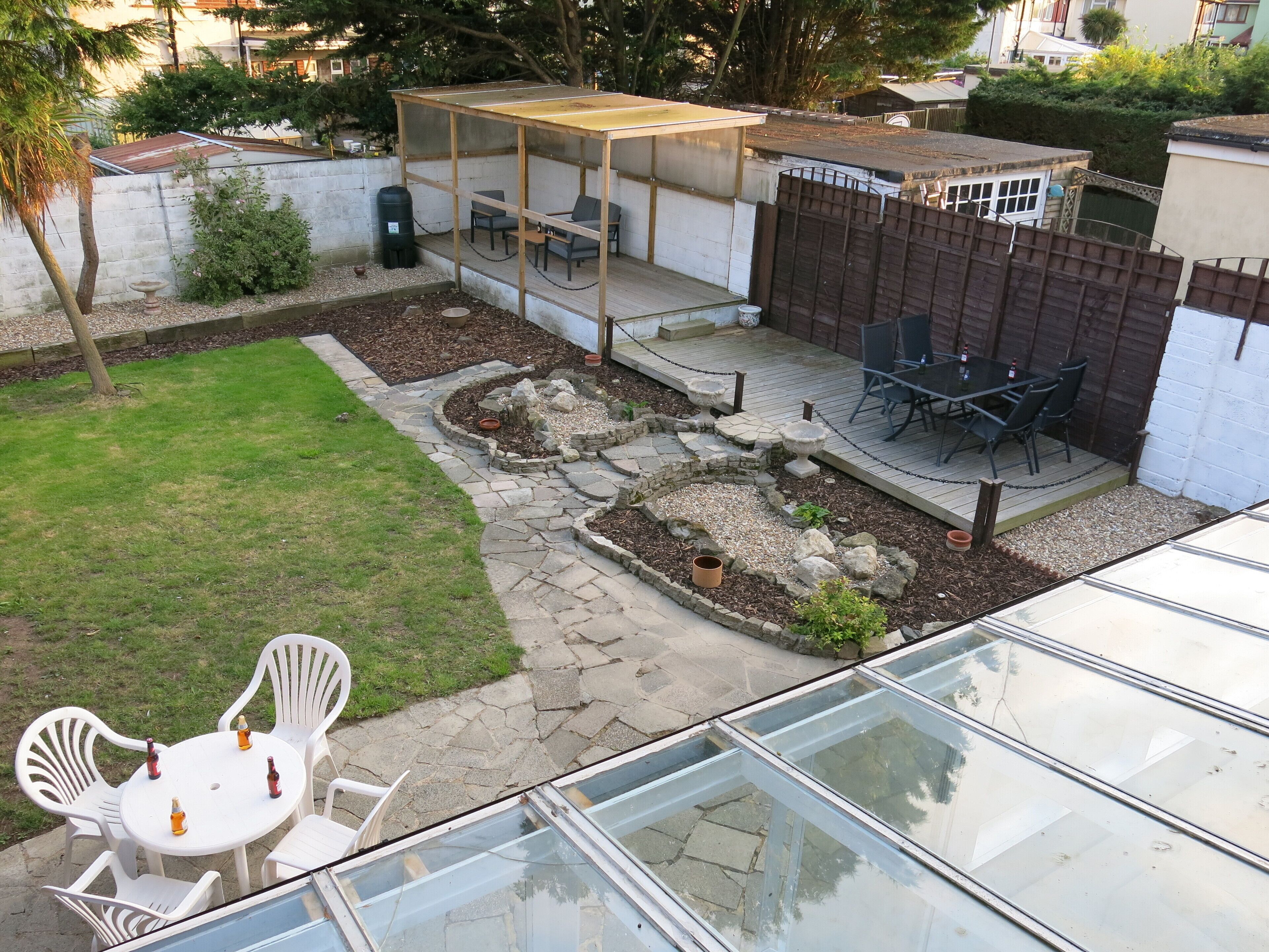 A backyard with a patio area, a covered seating area, and a glass-enclosed space.