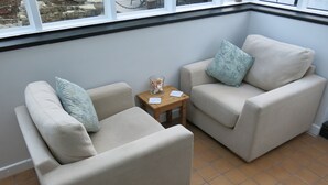 Ein Eckzimmer mit zwei beigen Sofas, einem kleinen Holztisch und Blick durch ein Fenster.