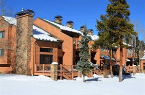Experience the charm of this rustic lodge, featuring a prominent chimney, multiple balconies, and a cozy covered outdoor area.