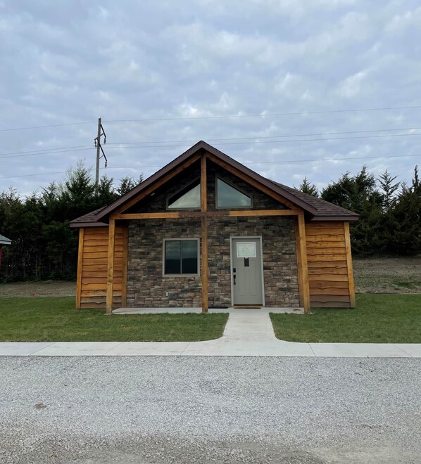 A single-story building with a stone facade, a gabled roof, and a front door.