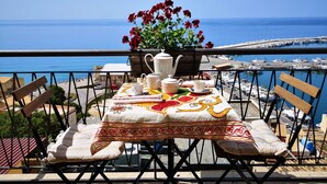 A balcony with a table set for tea, overlooking a marina and the sea. - The terraces (Sciacca)