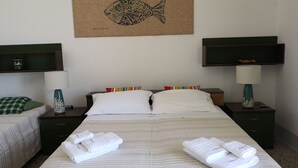 A hotel room with a bed, two nightstands, a wall-mounted TV, and a decorative fish artwork. - The terraces (Sciacca)