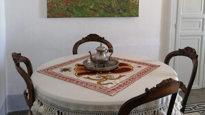 A dining table with a decorative tablecloth, a metal pitcher, and a patterned placemat. - The terraces (Sciacca)