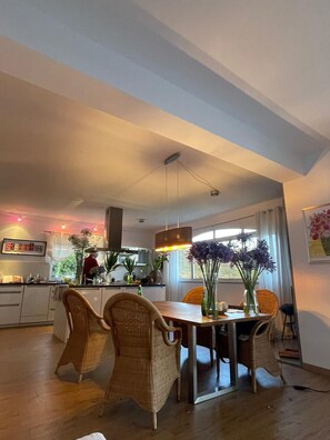 A dining area with wicker chairs, a wooden table, and a hanging pendant light. - Casa Oliva-Panorama: Large designer apartment, fantastic views, heated pool (Arco da Calheta)