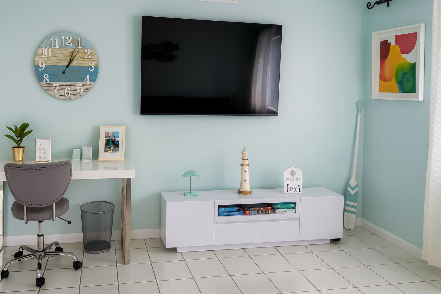 Un saló modern amb televisió de pantalla plana, un rellotge, una taula de treball, una cadira, una prestatgeria i objectes decoratius.