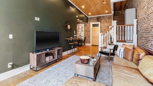 Een moderne woonkamer met een flatscreen-tv, een houten tv-meubel, een bank en een salontafel met popcorn.