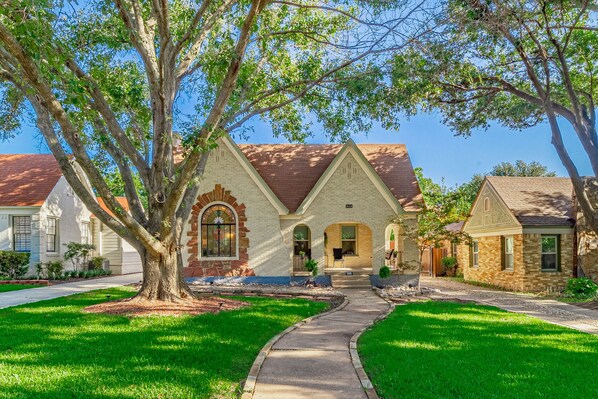 A residential house with a brick facade, a front porch, and a well-maintained lawn.