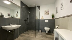 A modern bathroom with a glass shower enclosure, a white sink, and a toilet.