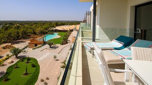 A balcony with a pool, lounge chairs, and a view of a landscaped area with trees and a pool. - Luxury south facing 3 bedroom apartment in Las Colinas Golf (Dehesa de Campoamor)