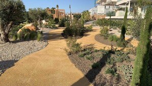 A landscaped pathway with gravel and plants, leading to a building with a modern design. - Luxury south facing 3 bedroom apartment in Las Colinas Golf (Dehesa de Campoamor)