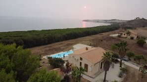 A residential area with a swimming pool, a small house, and a view of the sea.