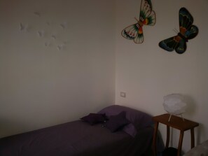 A bedroom with a single bed, a small table, and two butterfly wall decorations.