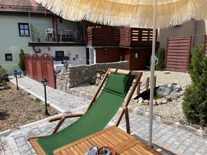 A wooden deck with a green cushioned chair, a table, and a stone wall. - Guest house with 3 apartments, quietly located in the town center (Feuchtwangen)