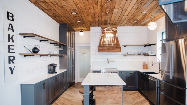Una cucina moderna con travi in legno, un'isola centrale ed elettrodomestici in acciaio inossidabile.