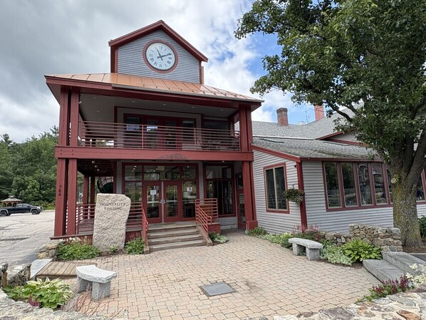A two-story building with a clock on the upper level, a sign reading "Hospitality Building," and a staircase leading to the entrance.