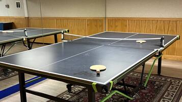 Una habitación con mesas de ping pong, alfombra estampada y paneles de madera.
