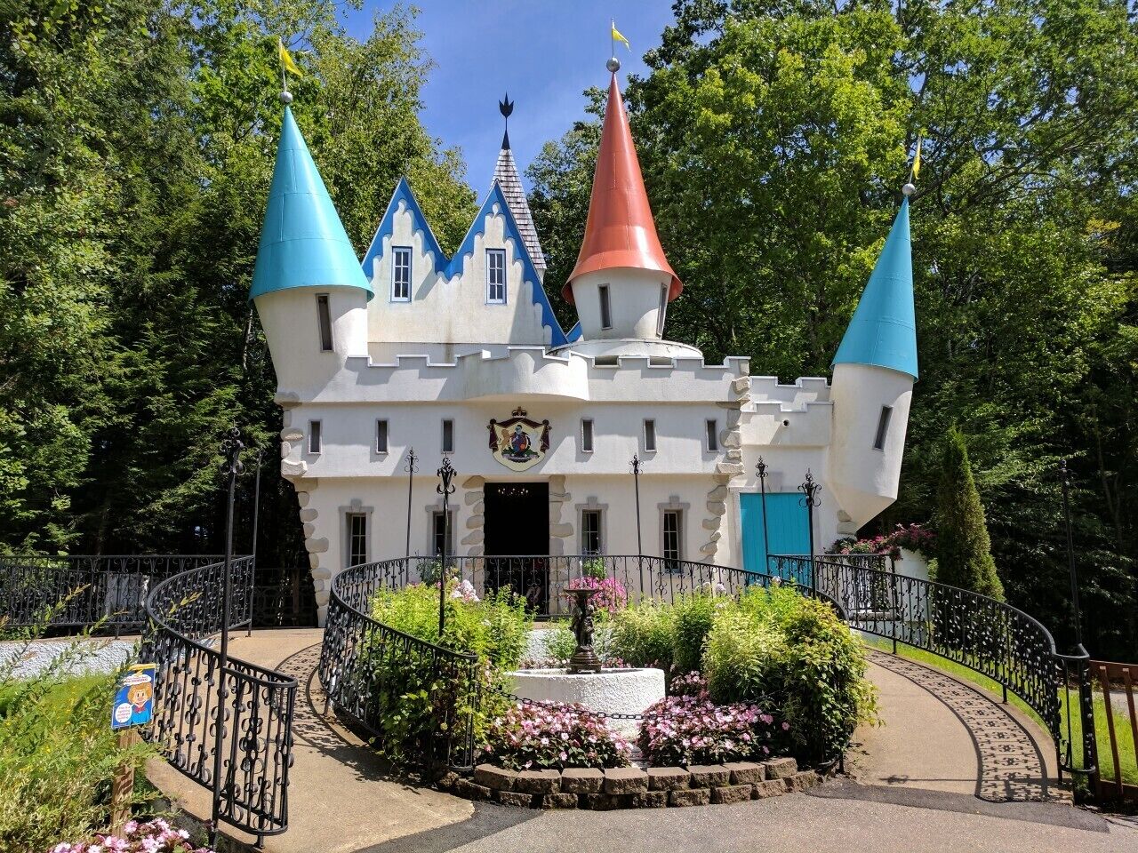 A castle-like building with multiple towers, a central entrance, and a surrounding garden with a fountain.