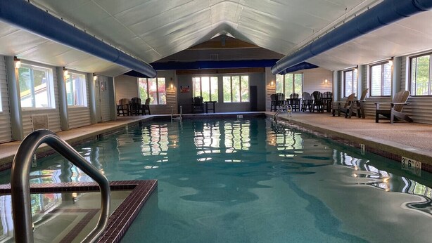En inomhuspool med klart vatten, en hoppställning och stolar runt poolen.