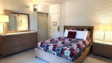 Un dormitorio con una cama de madera, un tocador, un espejo y una mesita de noche con una lámpara.