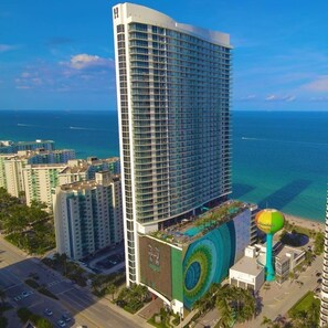 A high-rise hotel with a modern design, featuring a large pool area and a view of the ocean.