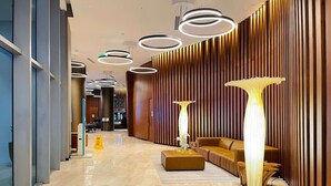 A modern lobby with a wooden wall, a sofa, and a tall floor lamp. - BeachFront Luxury Hotel | 3B OceanView Hyde Resort (Hollywood)