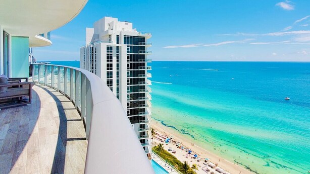 A balcony with a view of a beach and a tall building. - BeachFront Luxury Hotel | 3B OceanView Hyde Resort (Hollywood)