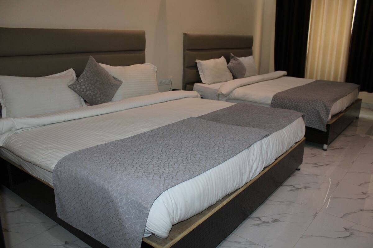 A hotel room with two beds, each with a headboard, a bedside table, and a nightstand.